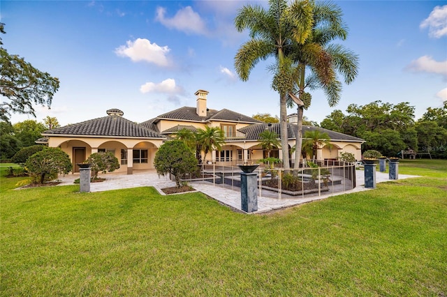 back of house featuring a patio, a lawn, a tile roof, and stucco siding