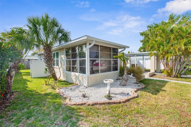 back of house featuring a sunroom and a lawn