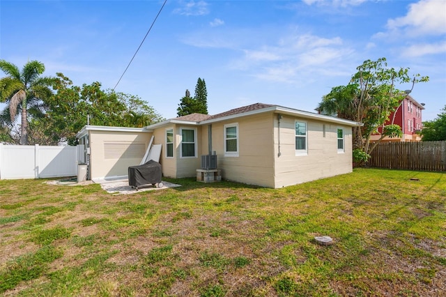 rear view of property with a lawn and central AC unit