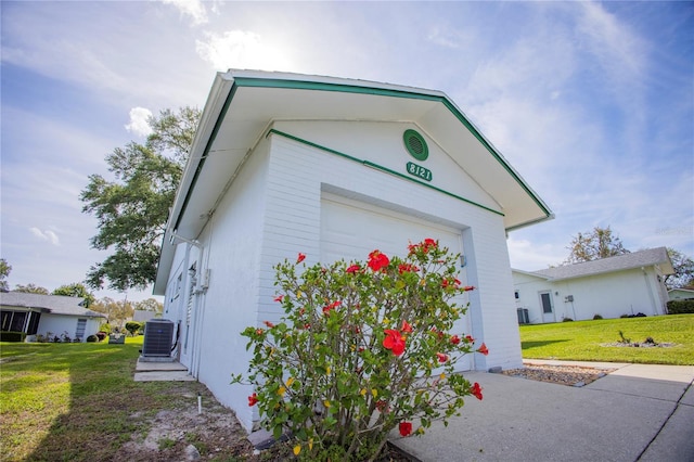 view of home's exterior with a garage, central AC, and a lawn