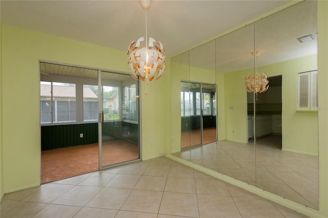 tiled empty room featuring a notable chandelier