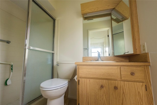 bathroom featuring a shower with shower door, vanity, and toilet