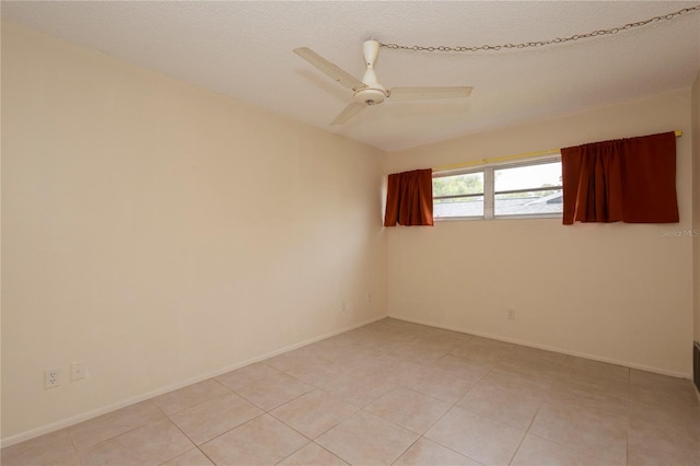 unfurnished room with ceiling fan, light tile patterned flooring, and a textured ceiling