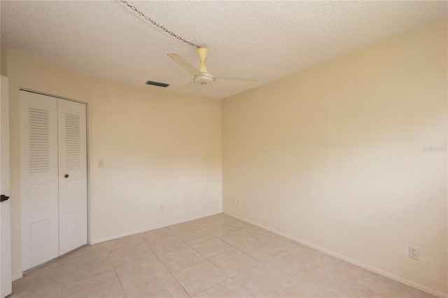 unfurnished bedroom featuring ceiling fan, a closet, a textured ceiling, and light tile patterned floors