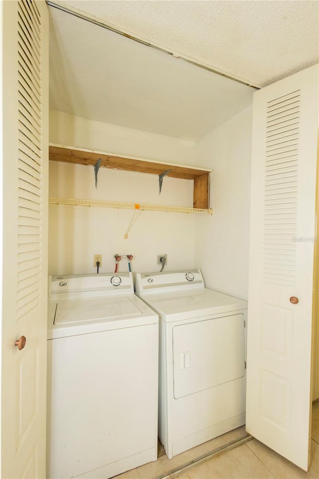 washroom with washer and dryer, a textured ceiling, and light tile patterned floors