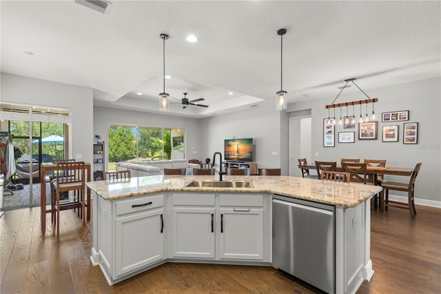 kitchen with a center island with sink, hanging light fixtures, hardwood / wood-style floors, and a raised ceiling