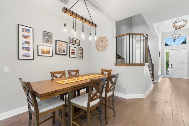 dining area with a notable chandelier and dark hardwood / wood-style flooring