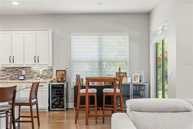 dining area with wine cooler and light hardwood / wood-style floors