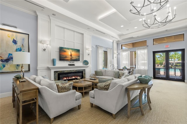 living room with a tray ceiling, a fireplace, light colored carpet, and a chandelier