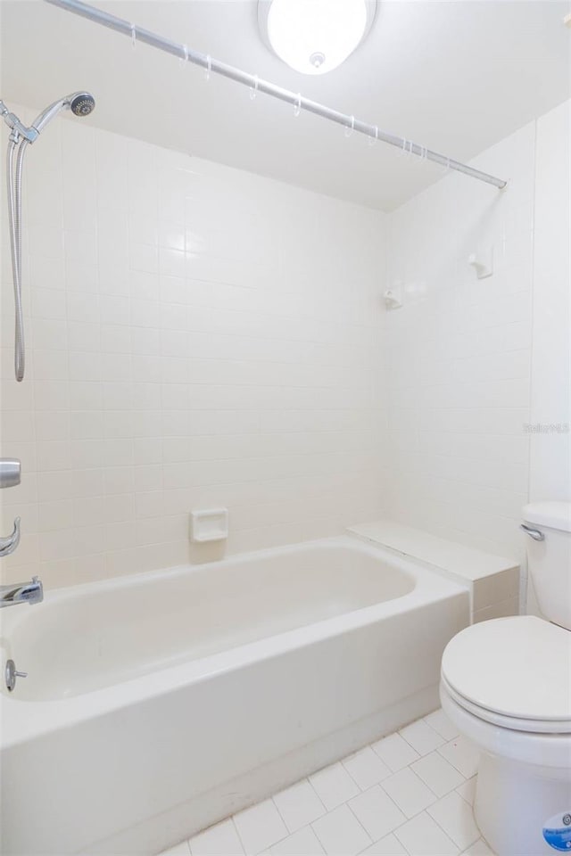 bathroom with tile floors, tiled shower / bath combo, and toilet