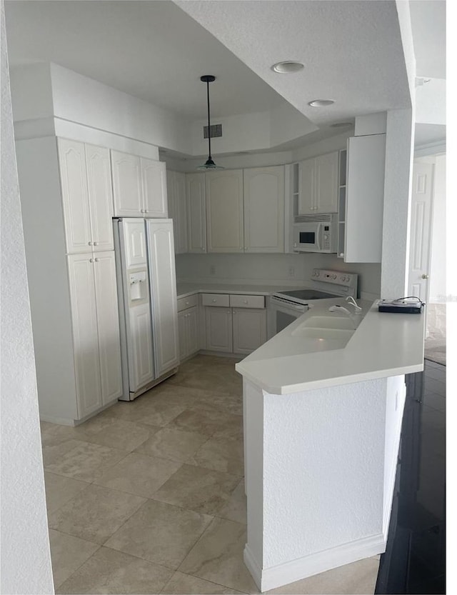 kitchen featuring light countertops, a peninsula, white appliances, visible vents, and decorative light fixtures