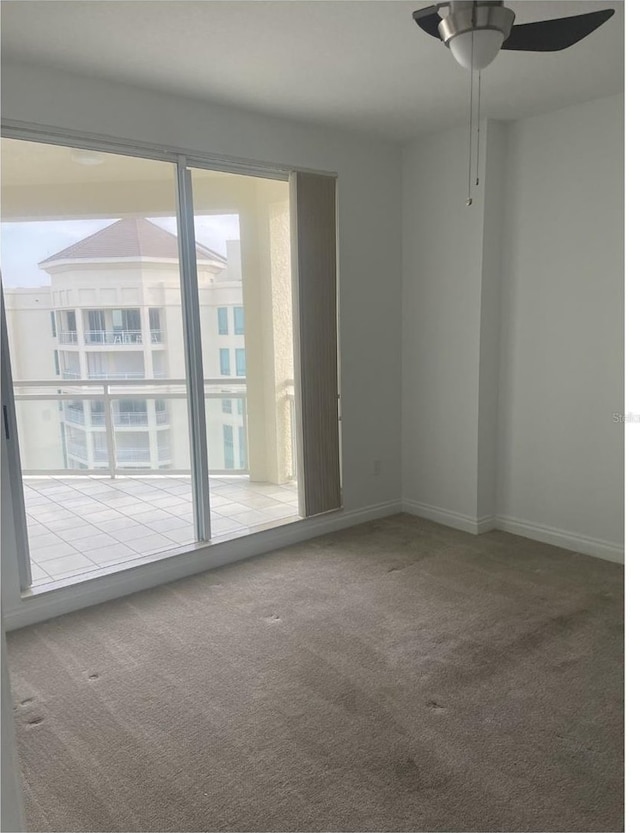 carpeted empty room with a ceiling fan and baseboards