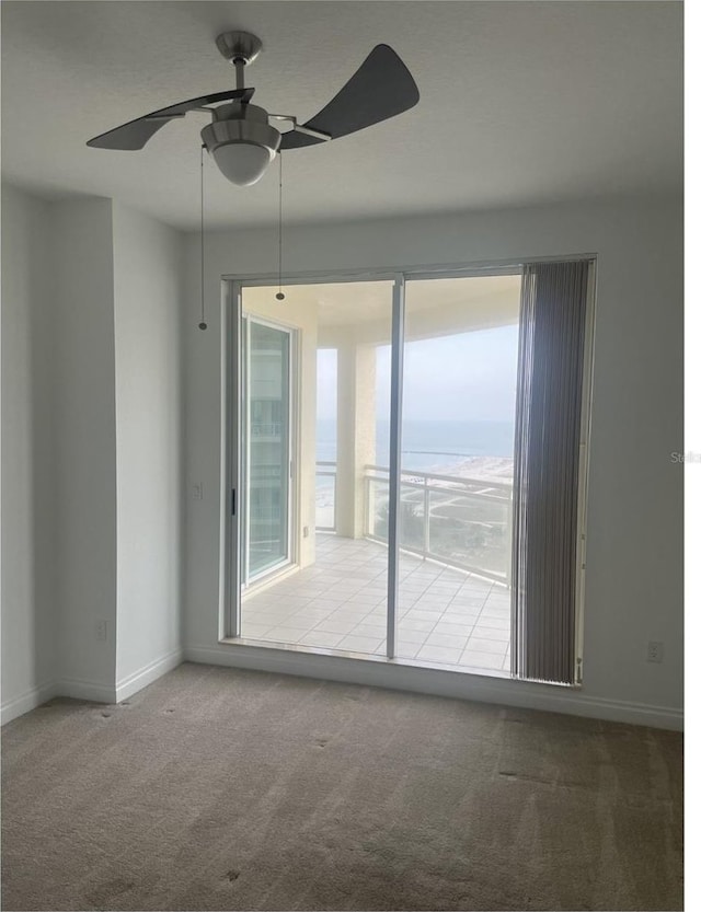 carpeted spare room with baseboards, a water view, and ceiling fan