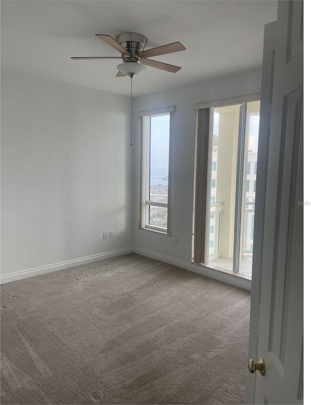 empty room featuring a ceiling fan, carpet, and baseboards