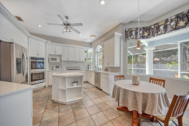 kitchen featuring tasteful backsplash, stainless steel appliances, ceiling fan, sink, and white cabinetry