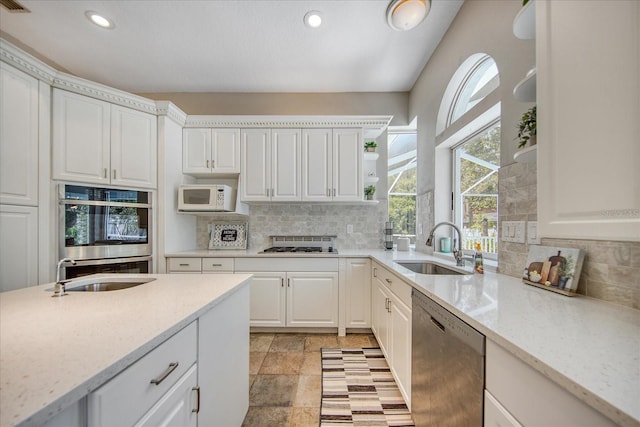 kitchen featuring white cabinetry, sink, light stone counters, decorative backsplash, and appliances with stainless steel finishes