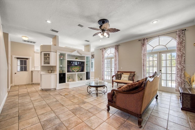 living room featuring french doors, ceiling fan, ornamental molding, a textured ceiling, and light tile patterned flooring