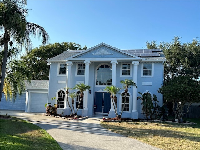 greek revival house featuring a garage, a front yard, and solar panels