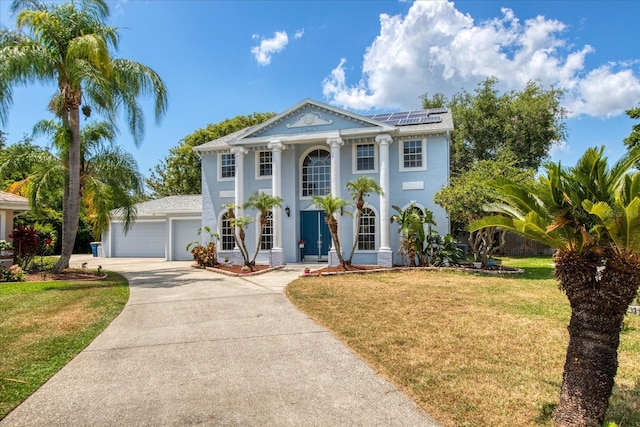 greek revival inspired property featuring solar panels, a garage, and a front yard