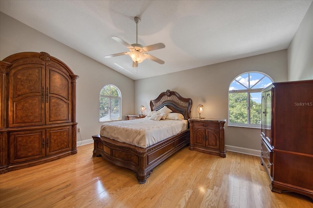 bedroom featuring multiple windows, ceiling fan, light hardwood / wood-style floors, and lofted ceiling