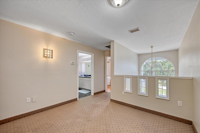 carpeted empty room featuring a textured ceiling