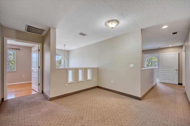 carpeted spare room with a healthy amount of sunlight and a textured ceiling