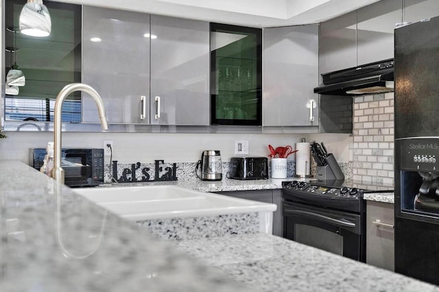 kitchen with tasteful backsplash, light stone countertops, and black appliances