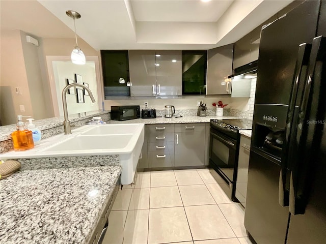 kitchen featuring light stone countertops, black appliances, light tile patterned floors, gray cabinets, and hanging light fixtures