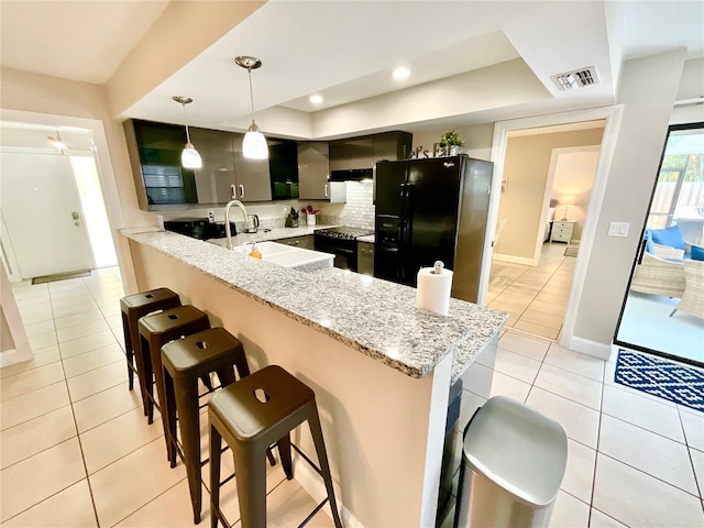 kitchen featuring kitchen peninsula, black fridge with ice dispenser, sink, hanging light fixtures, and stainless steel range with electric cooktop