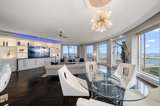 dining room with ceiling fan with notable chandelier, a water view, plenty of natural light, and crown molding