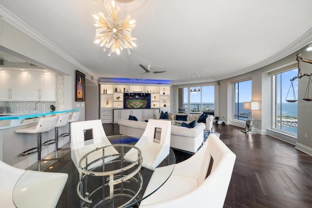 living room with ceiling fan with notable chandelier, crown molding, plenty of natural light, and dark parquet floors