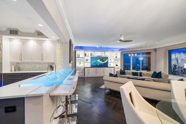 living room with dark parquet floors, ceiling fan, ornamental molding, and sink