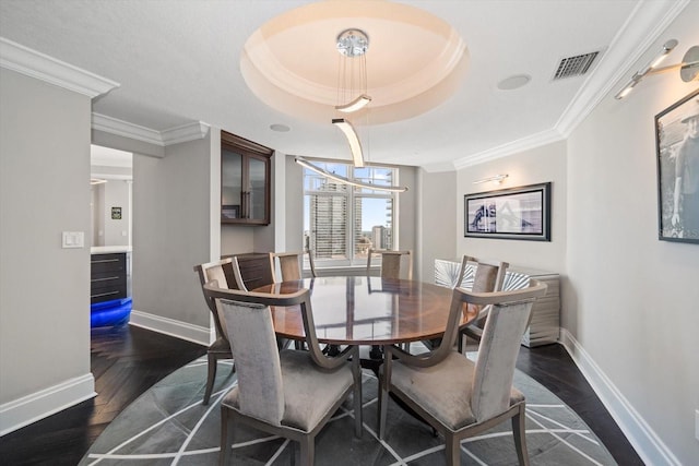 dining space with ornamental molding, a tray ceiling, an inviting chandelier, and dark wood-type flooring