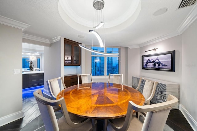 dining space featuring a raised ceiling and ornamental molding