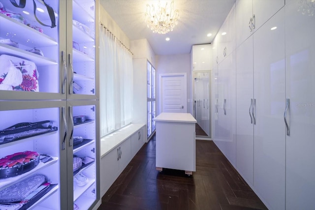 spacious closet featuring a notable chandelier and dark parquet flooring