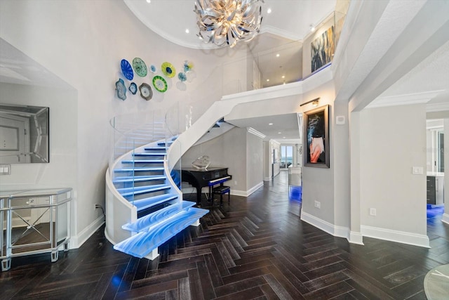 entrance foyer featuring dark parquet flooring, crown molding, a towering ceiling, and a notable chandelier