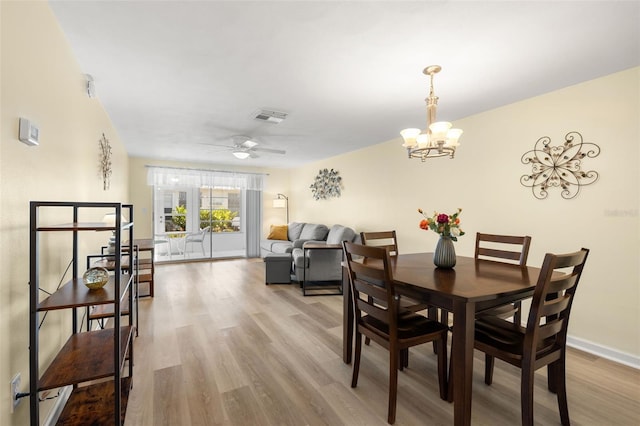 dining area with ceiling fan with notable chandelier and light hardwood / wood-style floors