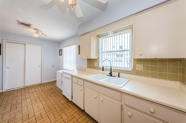 kitchen featuring white dishwasher, a textured ceiling, sink, tasteful backsplash, and ceiling fan