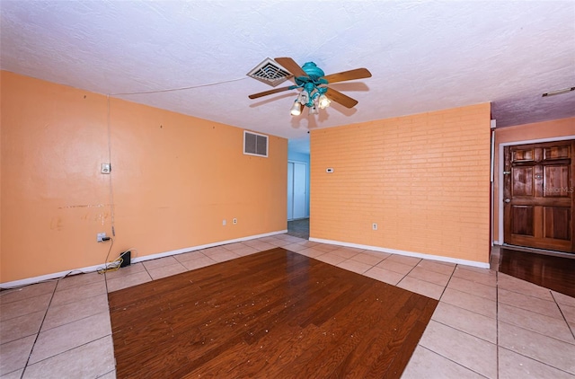 tiled spare room with a textured ceiling and ceiling fan