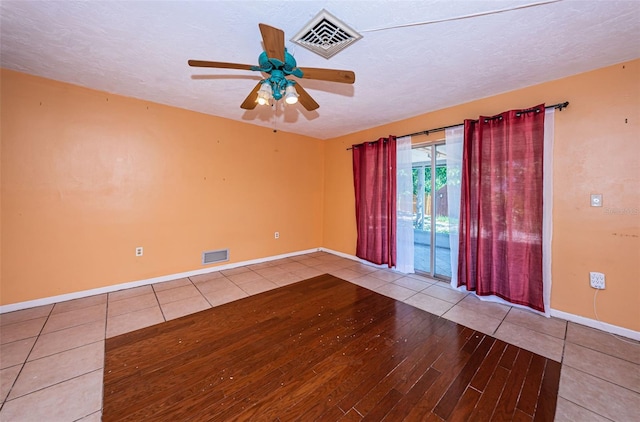 empty room with tile flooring, ceiling fan, and a textured ceiling