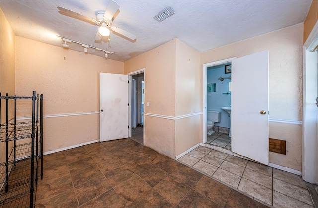 tiled spare room with track lighting, ceiling fan, and a textured ceiling