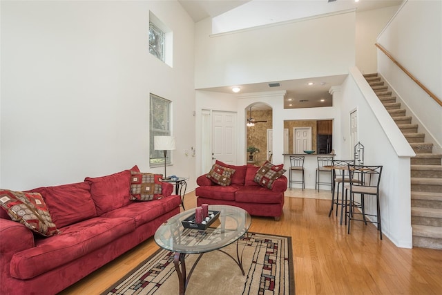 living room featuring a high ceiling, wood-type flooring, and ceiling fan