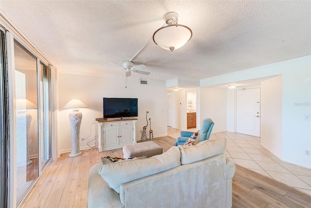 living room with ceiling fan, light wood-type flooring, and a textured ceiling