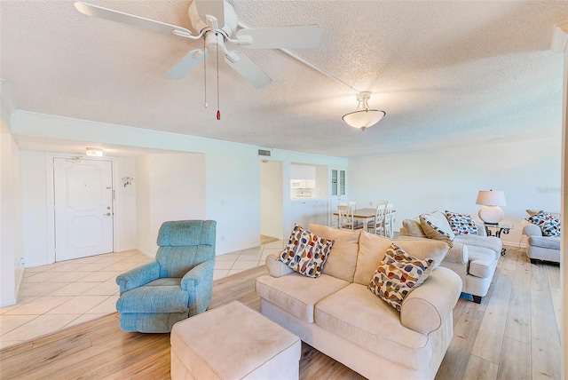 living room featuring ceiling fan, a textured ceiling, and light wood-type flooring