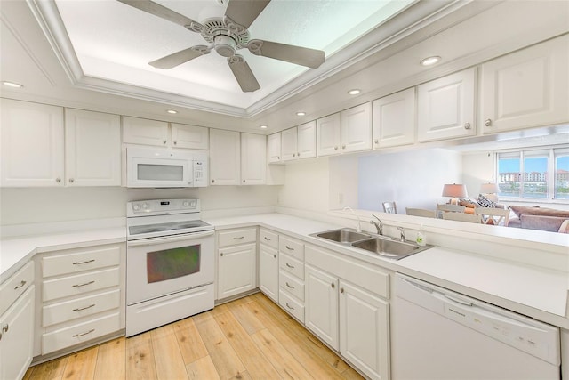 kitchen featuring a tray ceiling, white cabinetry, sink, and white appliances