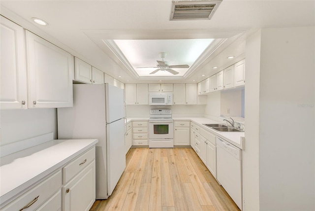 kitchen with sink, a raised ceiling, light hardwood / wood-style flooring, white appliances, and white cabinets