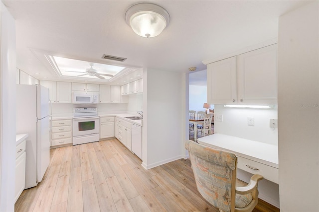 kitchen with light wood-type flooring, white appliances, a raised ceiling, ceiling fan, and white cabinetry