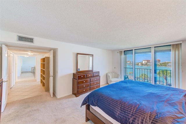 carpeted bedroom with expansive windows, access to exterior, and a textured ceiling