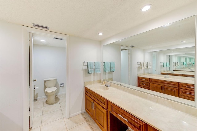 bathroom with tile patterned flooring, a textured ceiling, vanity, and toilet