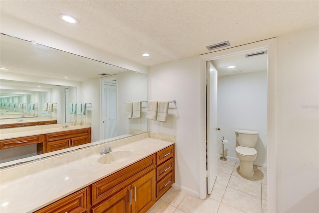 bathroom featuring tile patterned flooring, vanity, a textured ceiling, and toilet